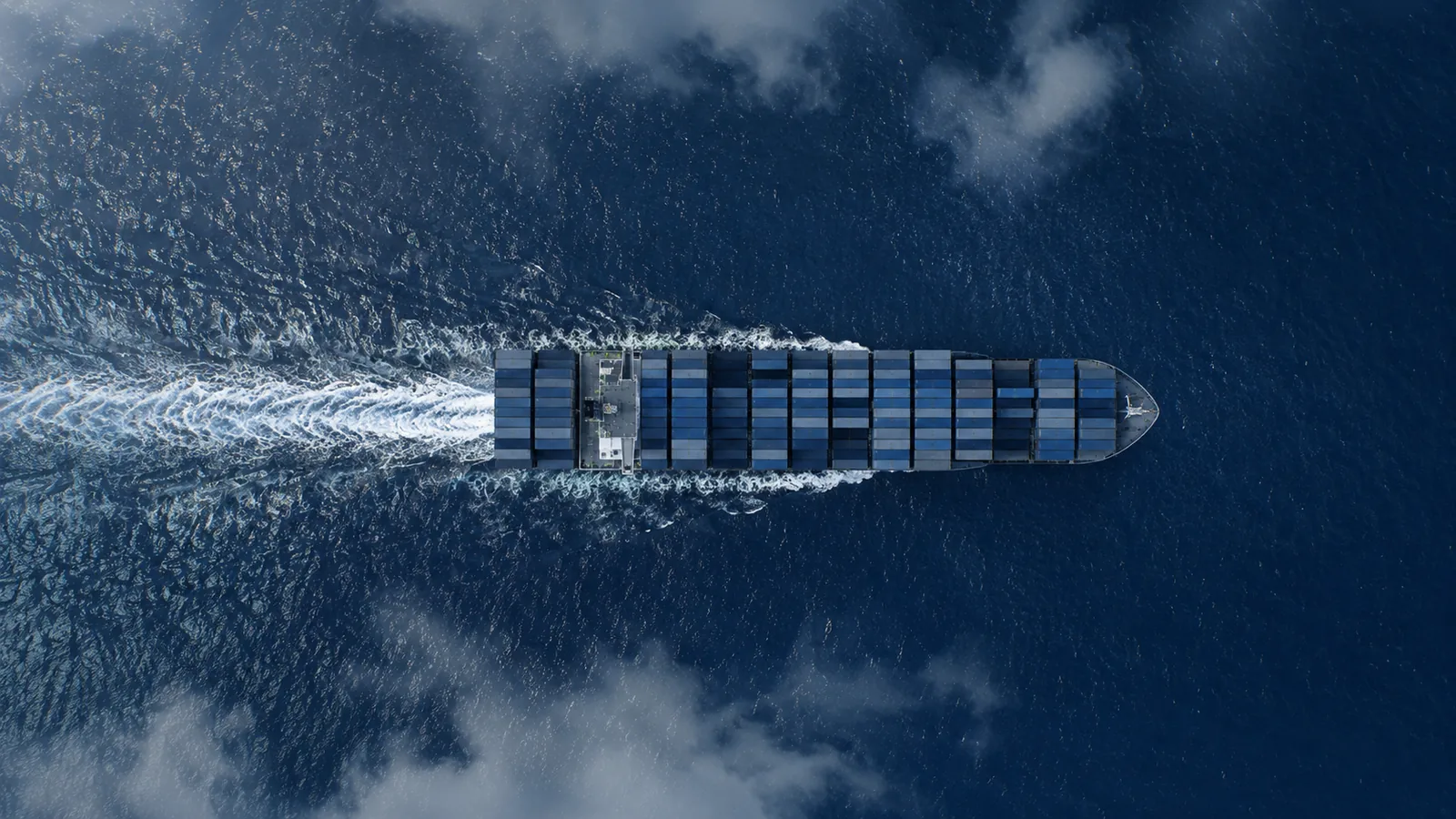 Vista aérea de un buque portacontenedores navegando en mar abierto, imagen que ilustra el comercio internacional de mercancías entre países.