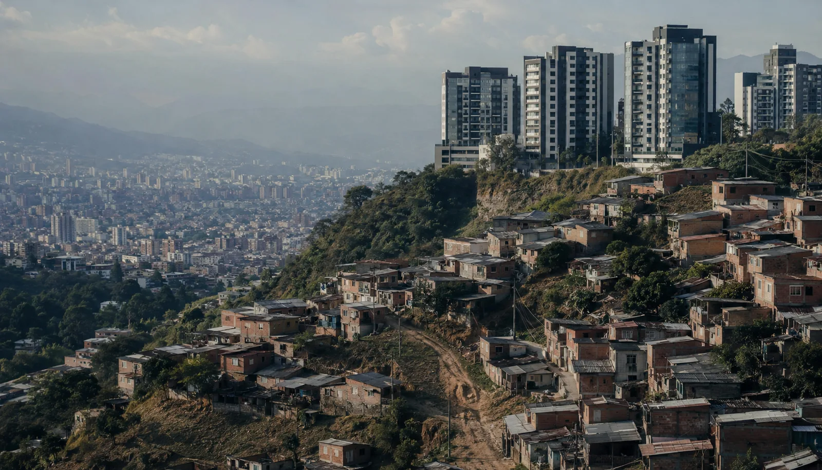 Ladera de una ciudad colombiana con torres modernas junto a un barrio popular, imagen que evoca la desigualdad y la economía política.
