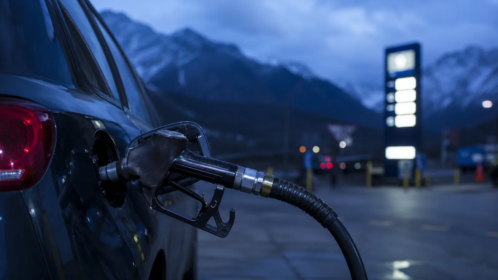 Surtidor de gasolina en una estación de servicio andina al atardecer con un vehículo repostando, metáfora de la elasticidad: la demanda de gasolina apenas cambia aunque suba el precio