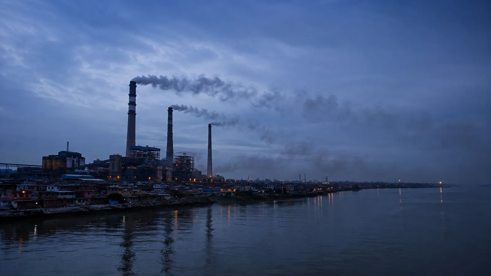 Chimeneas industriales al atardecer emiten humo que se dispersa sobre un río y un vecindario, ejemplo de externalidad negativa en economía.
