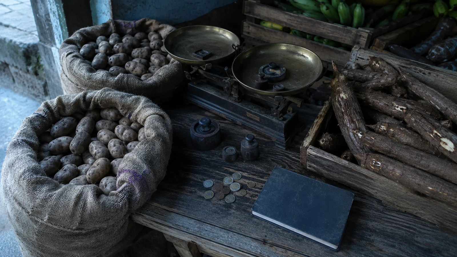 Puesto de plaza de mercado con bultos de papa, balanza de pesas y monedas, imagen de la economía de mercado como mecanismo de coordinación
